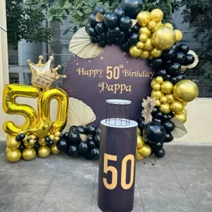 Black and gold 50th birthday balloon arch decoration with Happy Birthday Pappa backdrop and crown balloon in Indore
