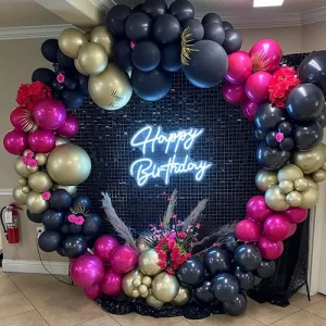 Black, magenta and gold circular balloon wreath birthday decoration with sequin backdrop and rose floral accents in Indore