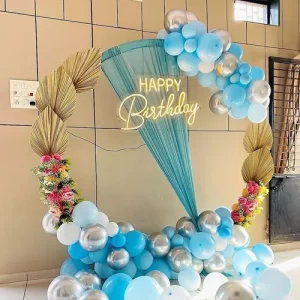 Blue and silver circular balloon arch birthday decoration with boho drape, dried palm leaves and florals in Indore