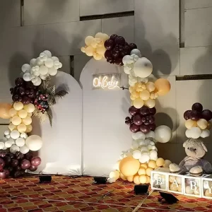 Birthday balloon decoration with burgundy, cream and gold garland and glowing neon sign in Indore