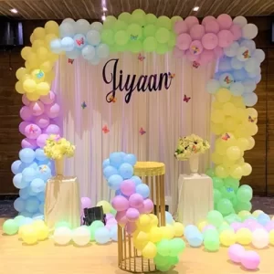 Birthday balloon decoration with pastel rainbow arch and personalised name backdrop in Indore