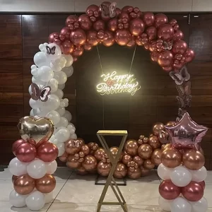Rose gold and white balloon arch birthday decoration with butterfly accents and Happy Birthday neon script in Indore