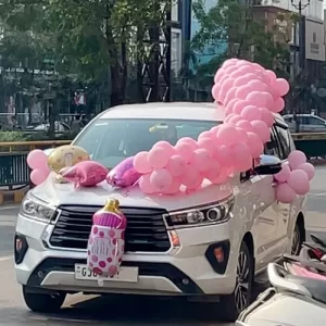Pink balloon garland with It's a Girl foil balloon car decoration on white SUV in Indore