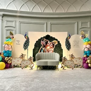 Radha Krishna naming ceremony peacock decoration with white backdrop arch and colorful balloons in Indore